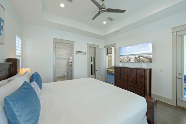 bedroom with ensuite bath, ceiling fan, a tray ceiling, and hardwood / wood-style floors