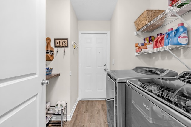 laundry area with washing machine and clothes dryer and light hardwood / wood-style flooring