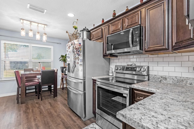 kitchen featuring light stone counters, dark brown cabinetry, stainless steel appliances, dark hardwood / wood-style flooring, and pendant lighting