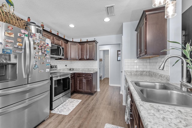 kitchen with tasteful backsplash, sink, light hardwood / wood-style flooring, appliances with stainless steel finishes, and dark brown cabinets