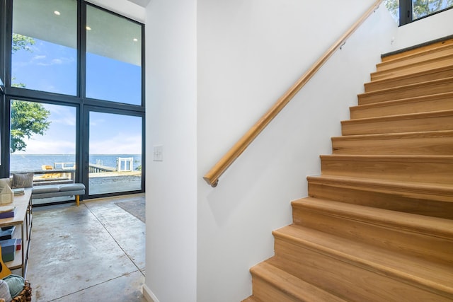 103 Native Tree Ln, Santa Rosa Beach, FL 32459 - staircase featuring a water view, a towering ceiling, and concrete floors