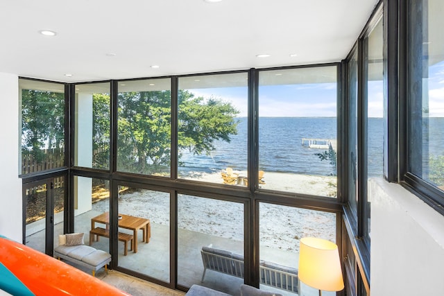 sunroom / solarium featuring a beach view and a water view