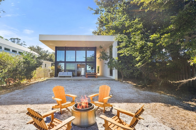 rear view of property featuring a patio and an outdoor fire pit