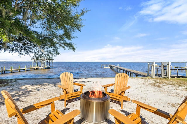 exterior space featuring a view of the beach, a water view, and an outdoor fire pit