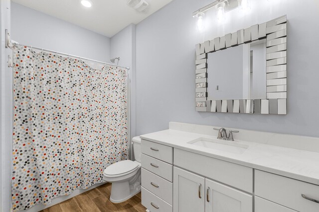 bathroom with toilet, vanity, wood-type flooring, and a shower with shower curtain