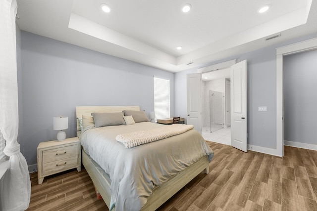 bedroom with wood-type flooring and a raised ceiling