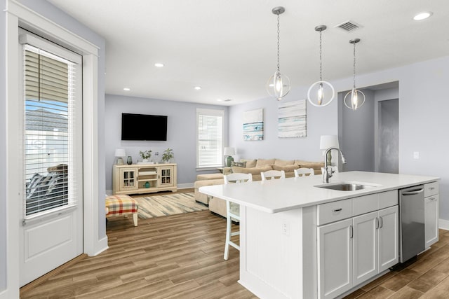 kitchen featuring sink, hanging light fixtures, plenty of natural light, and an island with sink