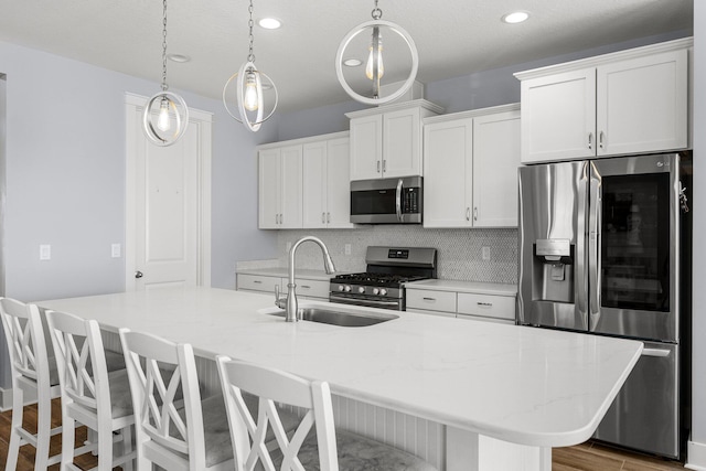 kitchen with appliances with stainless steel finishes, white cabinets, sink, and a center island with sink