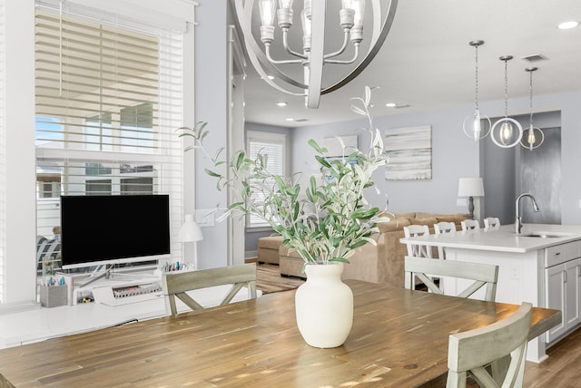 dining space featuring hardwood / wood-style flooring, sink, and an inviting chandelier