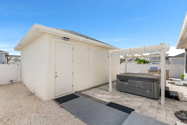 view of outdoor structure with a hot tub and a pergola