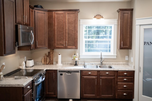 kitchen with light stone counters, appliances with stainless steel finishes, and sink