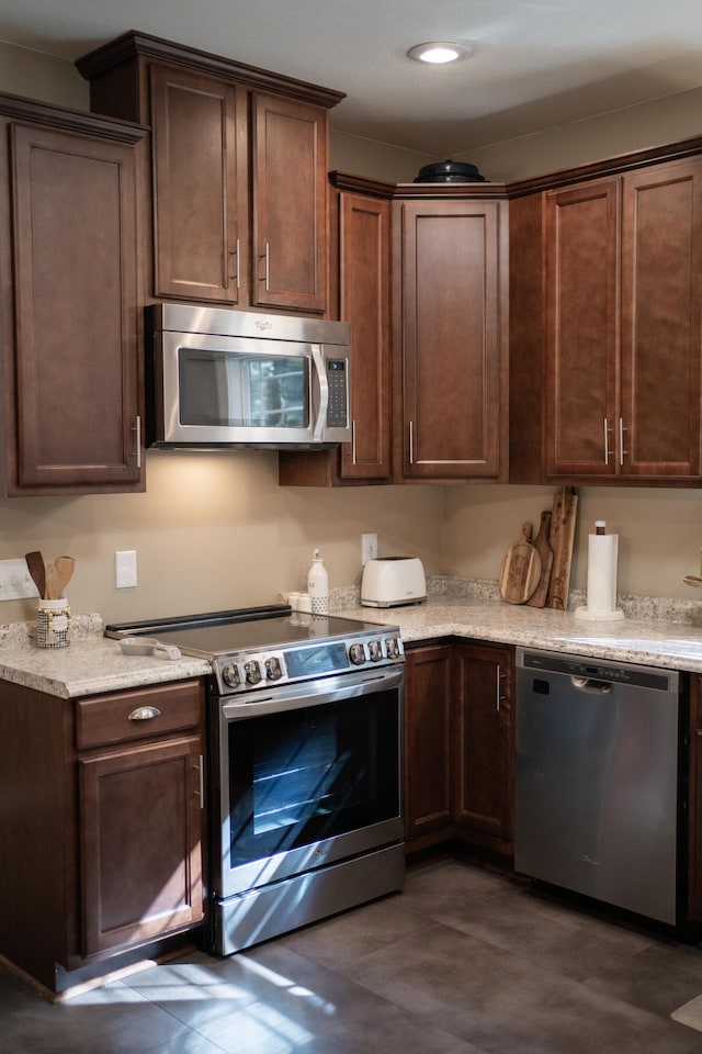 kitchen featuring light stone countertops, appliances with stainless steel finishes, and dark brown cabinetry