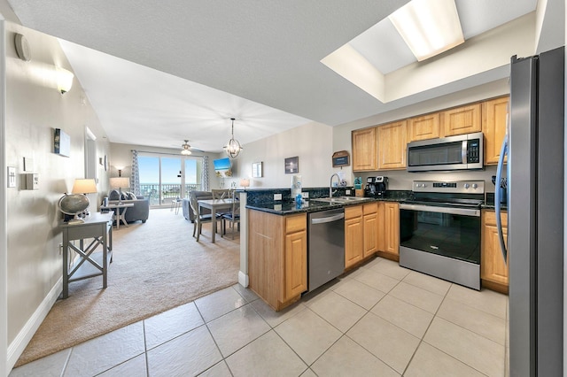 kitchen featuring stainless steel appliances, sink, light tile patterned flooring, kitchen peninsula, and pendant lighting