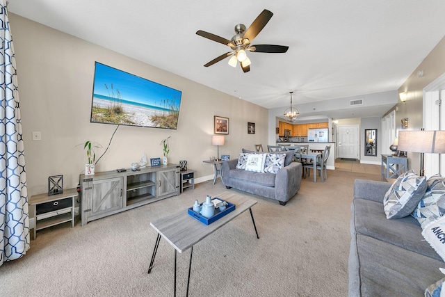 living room featuring ceiling fan with notable chandelier and carpet flooring