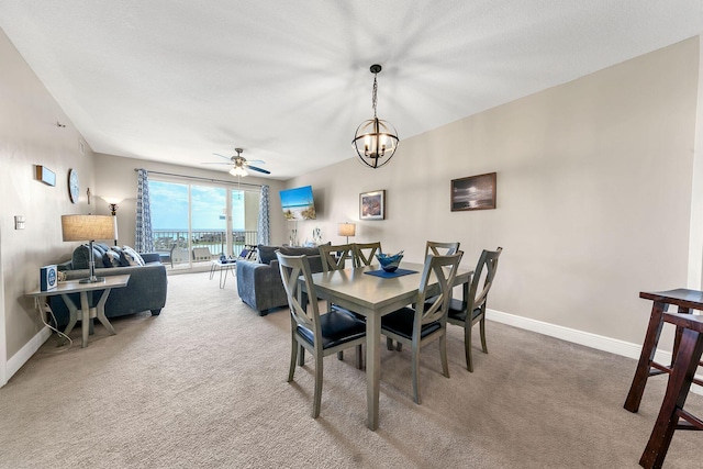 dining area featuring ceiling fan with notable chandelier and carpet flooring