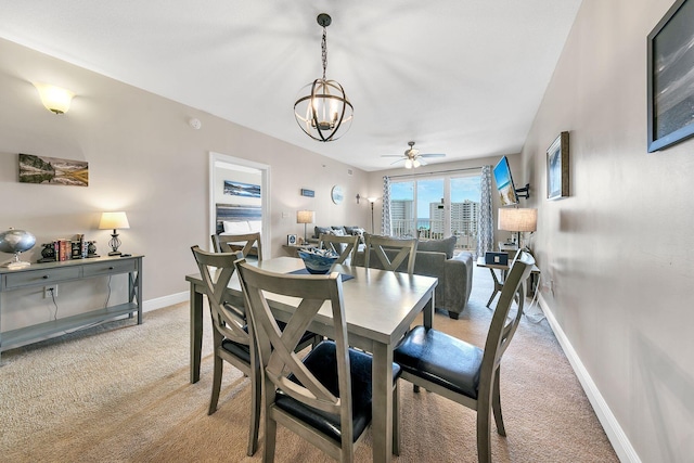 carpeted dining area featuring ceiling fan with notable chandelier