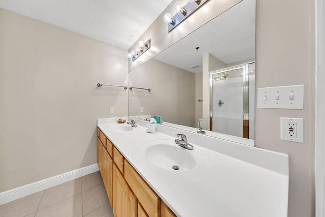 bathroom with tile patterned floors, a shower with door, vanity, and a textured ceiling