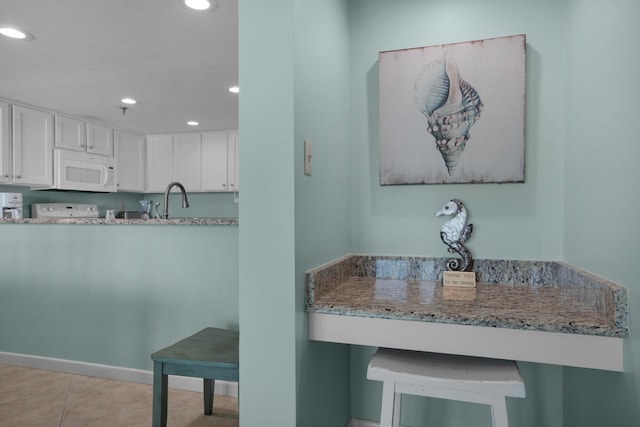 kitchen featuring light stone counters, light tile patterned floors, kitchen peninsula, and white cabinetry