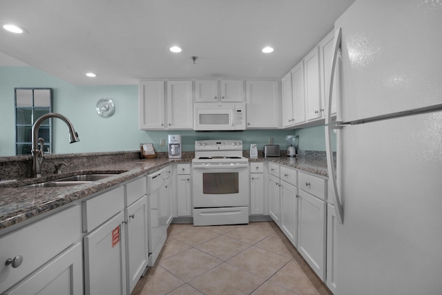 kitchen featuring dark stone countertops, white appliances, sink, light tile patterned flooring, and white cabinetry