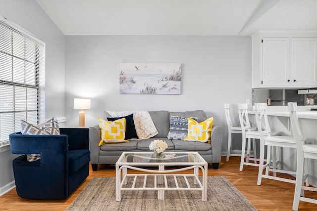 living room featuring baseboards, lofted ceiling, and light wood-type flooring