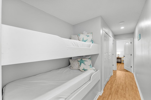 bedroom with light wood-style floors, a closet, and baseboards