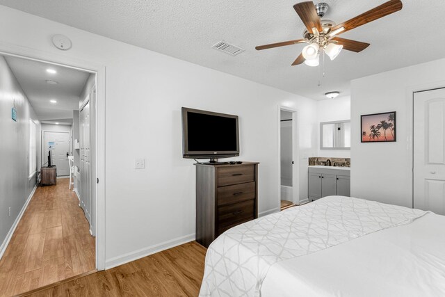 bedroom with baseboards, visible vents, connected bathroom, and light wood-style flooring
