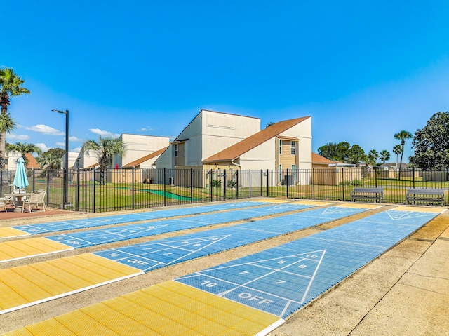view of property's community with shuffleboard, fence, and uncovered parking
