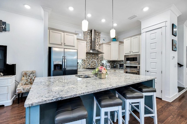 kitchen featuring an island with sink, appliances with stainless steel finishes, wall chimney exhaust hood, and dark hardwood / wood-style flooring