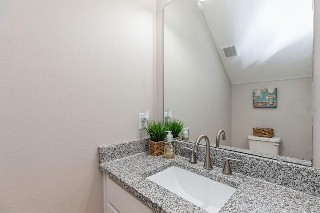 bathroom with vanity, toilet, and vaulted ceiling