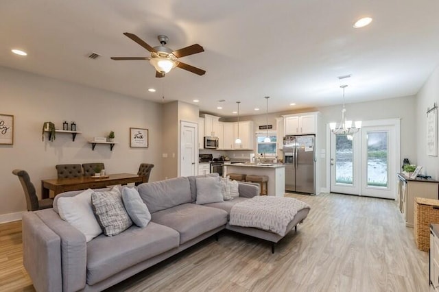 living room featuring light hardwood / wood-style flooring and ceiling fan with notable chandelier