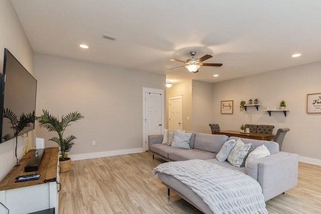 living room with light hardwood / wood-style flooring and ceiling fan