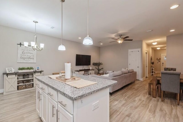 kitchen featuring a center island, pendant lighting, light wood-type flooring, white cabinets, and ceiling fan with notable chandelier