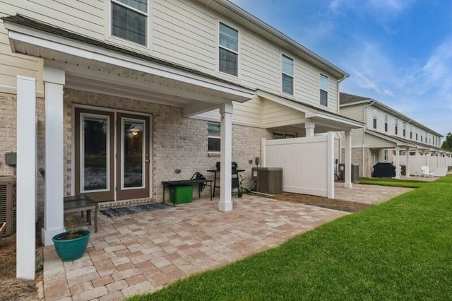 back of house featuring central air condition unit, a patio area, and a yard