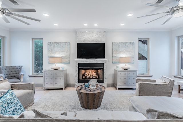 living room featuring ceiling fan, ornamental molding, and a fireplace