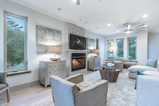 living room featuring ornamental molding, a fireplace, light hardwood / wood-style floors, and ceiling fan