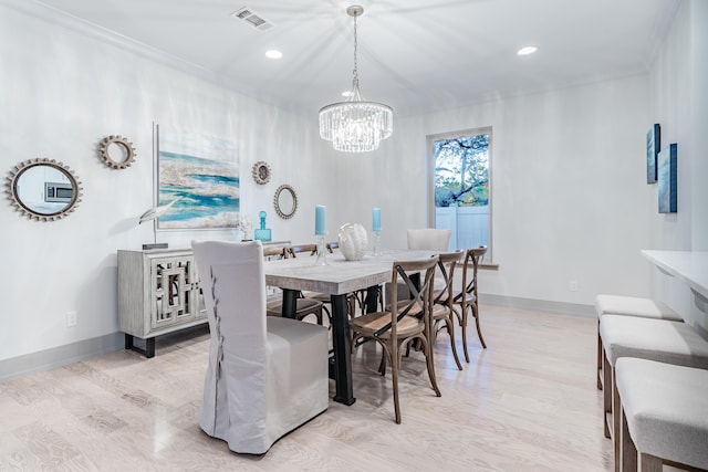 dining area featuring ornamental molding, light hardwood / wood-style flooring, and an inviting chandelier