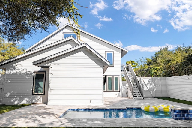 rear view of house with a patio area and a fenced in pool