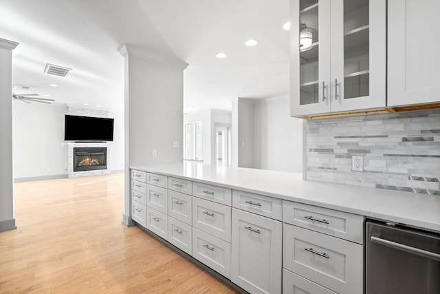 kitchen featuring ornamental molding, stainless steel dishwasher, light wood-type flooring, and backsplash