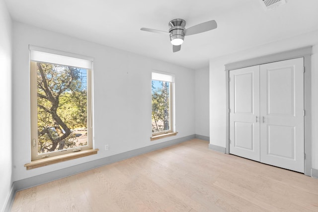 unfurnished bedroom with a closet, multiple windows, light hardwood / wood-style floors, and ceiling fan