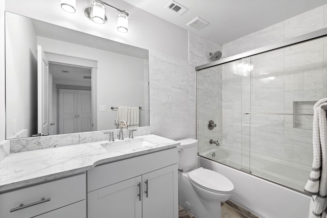 full bathroom featuring toilet, vanity, and shower / bath combination with glass door