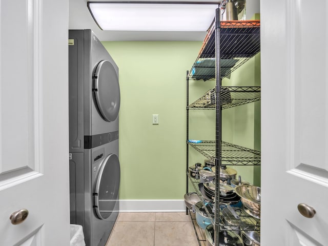 clothes washing area with light tile patterned flooring and stacked washer and dryer