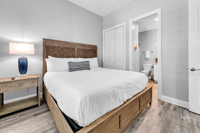 bedroom featuring a closet, ensuite bathroom, and light wood-type flooring