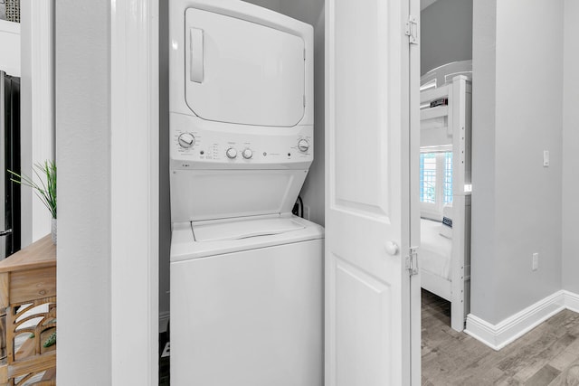 laundry area with light hardwood / wood-style flooring and stacked washer / dryer