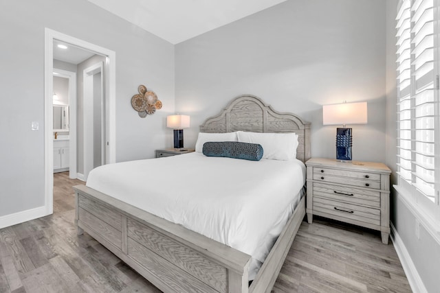 bedroom with ensuite bathroom and light wood-type flooring