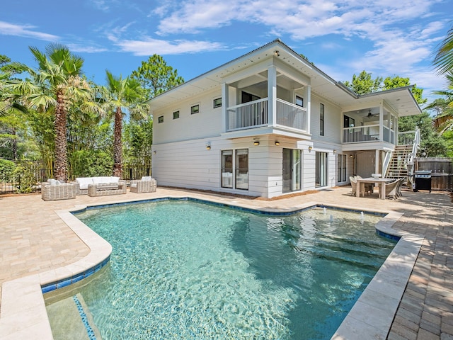 rear view of house with a fenced in pool, a balcony, and a patio