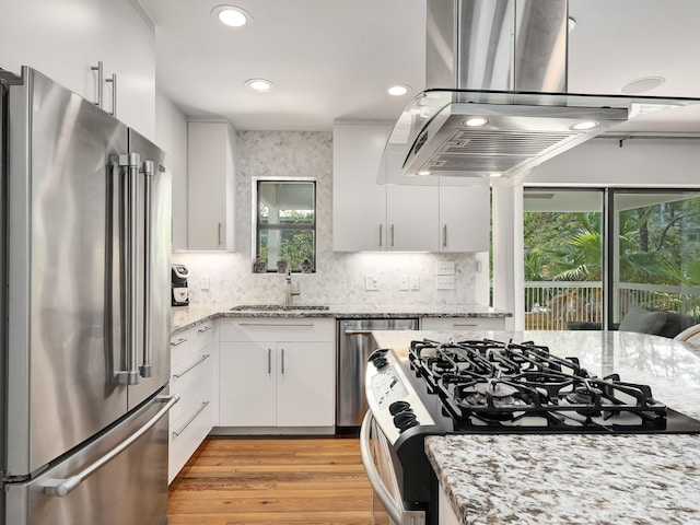 kitchen with white cabinets, sink, island range hood, plenty of natural light, and stainless steel appliances