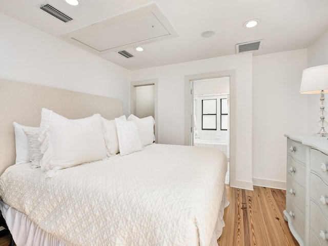 bedroom with light wood-type flooring and ensuite bath