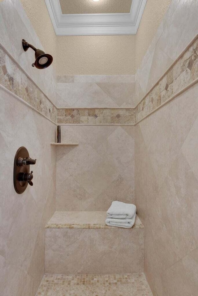 bathroom with tiled shower, a textured ceiling, and ornamental molding