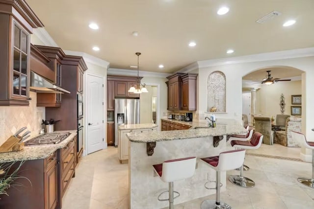 kitchen with kitchen peninsula, stainless steel appliances, decorative backsplash, a breakfast bar, and ventilation hood