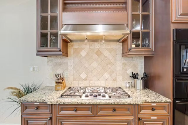 kitchen with light stone counters, tasteful backsplash, ventilation hood, and stainless steel gas stovetop